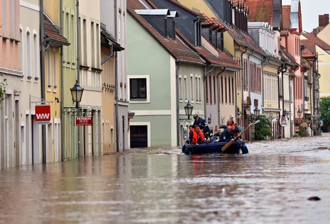 Bild einer &uuml;berfluteten Innenstadt, mittig f&auml;hrt ein Rettungsboot