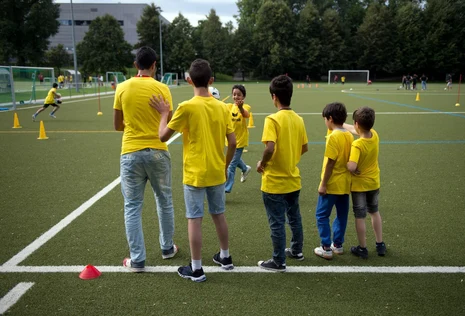 Bild von f&uuml;nf Kindern am Rande eines Fu&szlig;ballplatzes