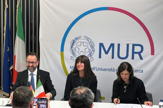 Zwei Männer und eine Frau sitzen an einem Tisch.