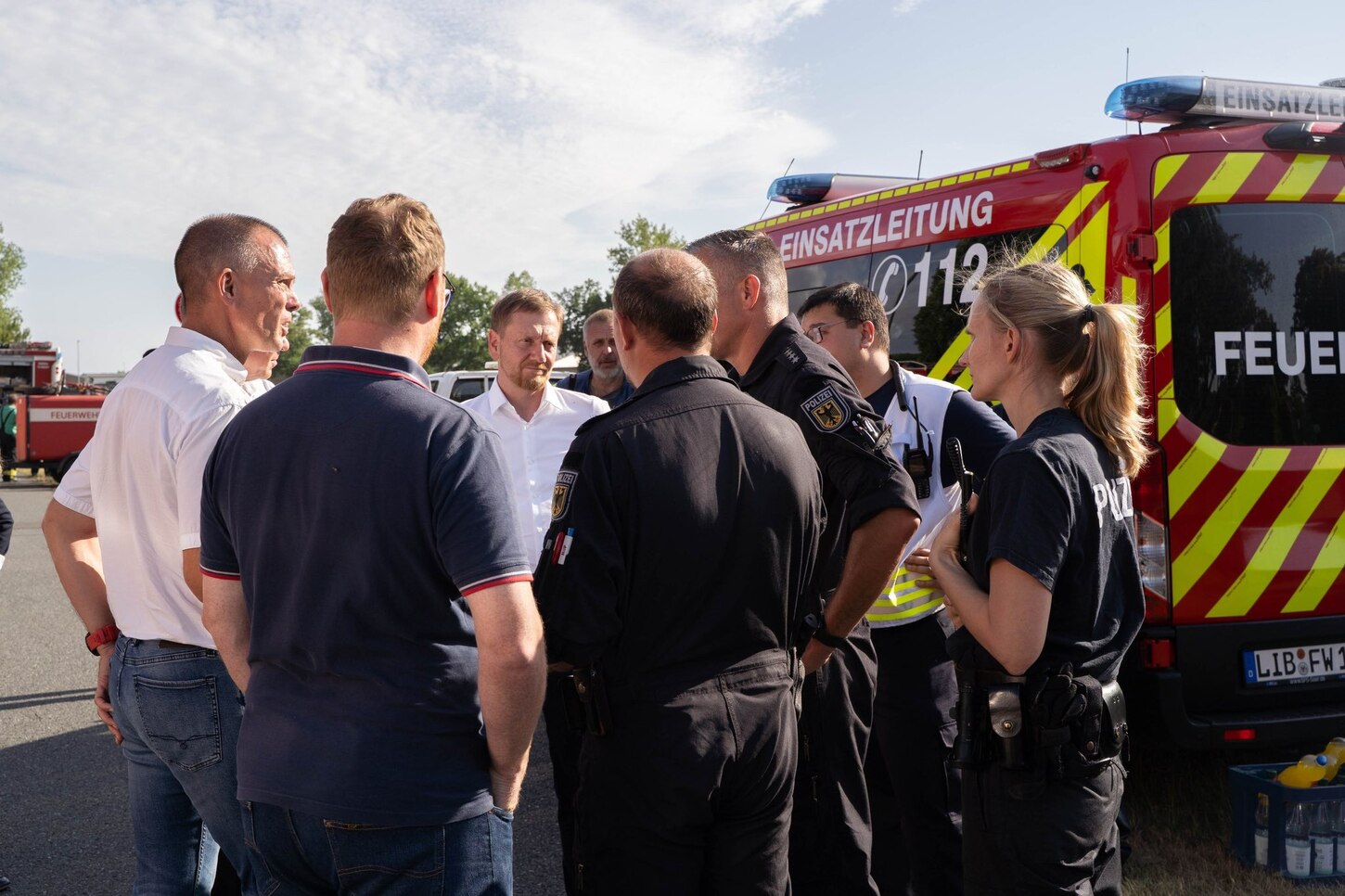 Männer und Frauen stehen vor einem Feuerwehrauto.